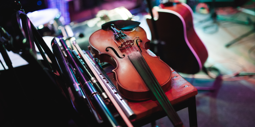 A fiddle, flutes and a guitar resting on a stage before a session